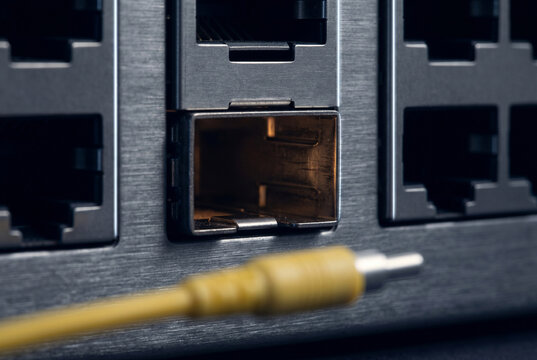 Graphic studio close-up focusing on an empty dark SFP+ cage slot, revealing internal metallic shielding walls with friction wear marks and a subtle warm 2700K internal component glow.
