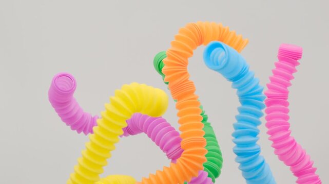 A colorful arrangement of stretchy ribbed colorful plastic flexible tubes against a white background, These are colorful plastic sensory fidget tubes designed for tactile stimulation and stress relief