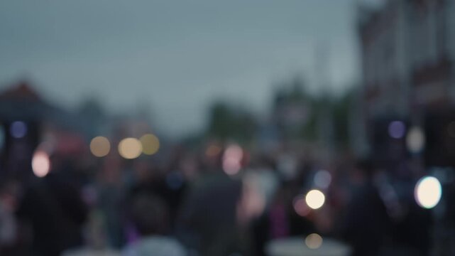 Cinematic shot of singer performing for crowd on city street.