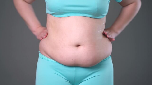 Overweight woman massaging belly fat, stomach self-massage. Weight loss, diet and anti-cellulite body care concept