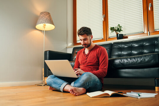 Student studying on laptop sitting on floor at home