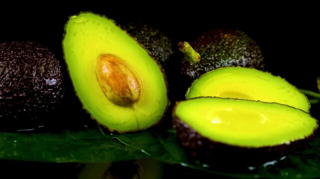 Macro shot of fresh sliced avocado with pit on dark background