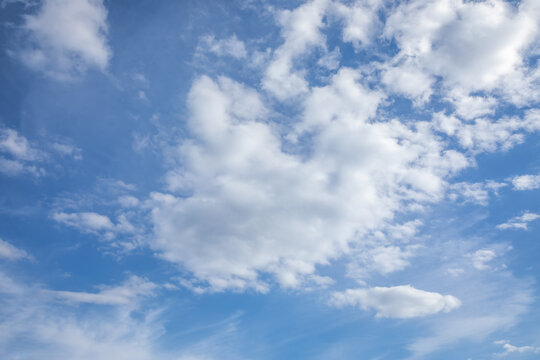 White fluffy clouds scattered across the vibrant blue sky creating a beautiful natural texture. Clean minimalist background with plenty of copy space for creative projects and advertising.