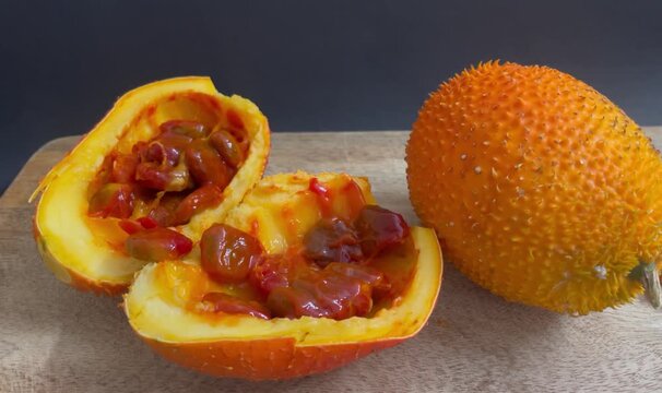 Fresh Gac Fruit Cut Open on Wooden Board Showing Red Seeds