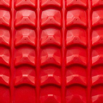 Red geometric plastic surface with raised shapes creating a textured pattern design