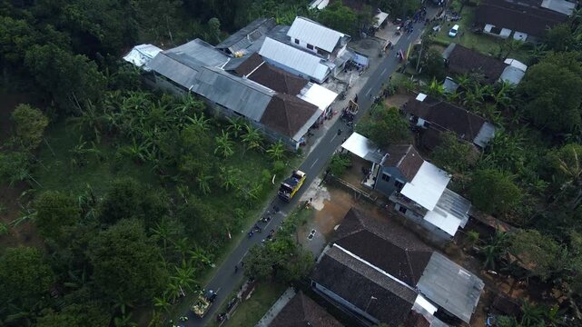 Aerial view of a parade of villagers walking along a small country road.