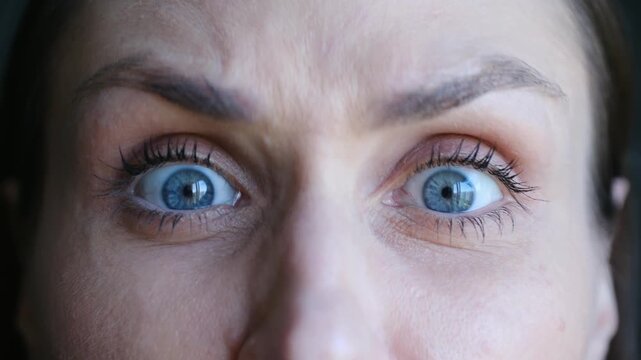 Close up furious woman face showing intense emotions, with beautiful blue eyes staring angrily, her brow furrowed, conveying rage, frustration, disapproval. Angry woman frowning with intense blue eyes