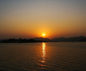 Fototapeta premium Scenic Sunset Lake With Mountain Silhouette View