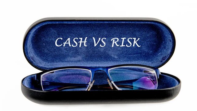 An open dark blue eyeglass case showcases blue framed eyeglasses resting on a white background. The important words Cash versus Risk are clearly visible inside the case lid