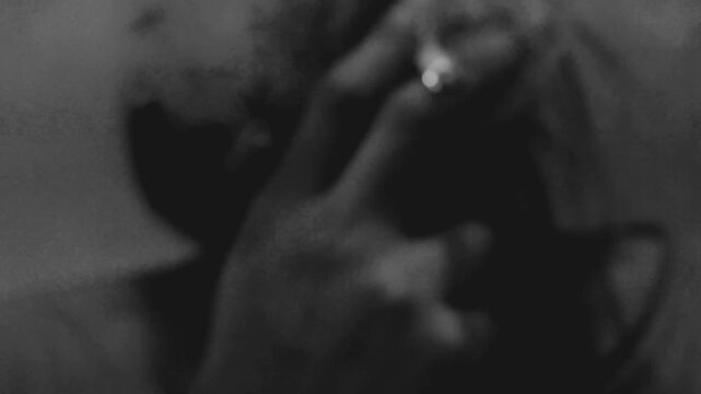 Close up of a depressed man smoking a cigarette in a low light room