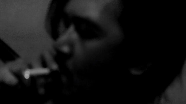 Close up of a depressed man smoking a cigarette in a low light room