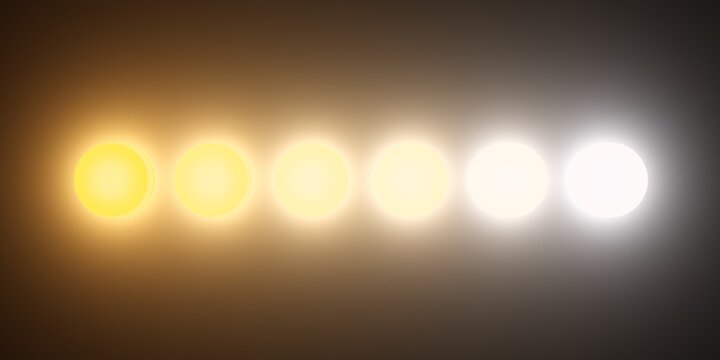 Row of round lights or lamps with different kelvin color temperatures from warm orange to cool blue on dark background, flat lay top view from above