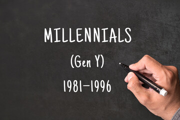 Fototapeta premium Millennials written on blackboard with hand, Gen Y born 1981 to 1996, generational demographics and social research concept