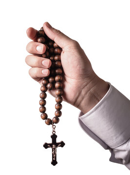 Isolated human hand holding a wooden rosary with crucifix representing faith and devotion