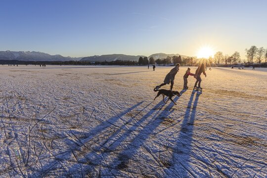 People skating on a lake, evening light, sunbeams, Staffelsee, Murnau, foothills of the Alps, Bavaria, Germany