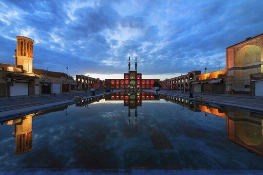 Amir Chaqmaq complex facade illuminated at sunrise and reflecting in a pond, Yzad, Yazd province, Iran