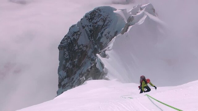 Mountaineer roped up while climbing a steep and snowy peak during a winter expedition