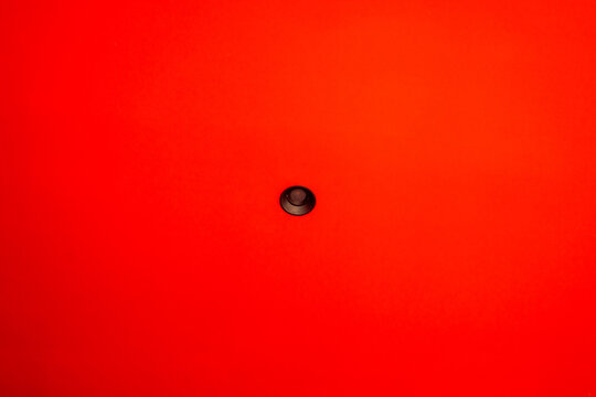 Modern recessed downlight centered on bright red ceiling with minimalist interior style and wide copy space for abstract background concepts.