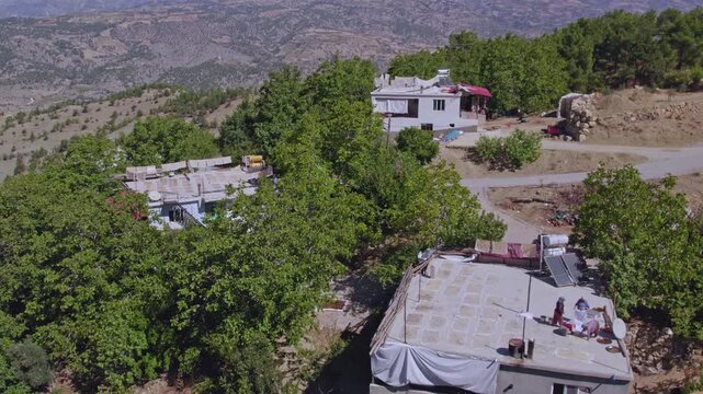 Aerial view of people sun-drying handmade food sheets on a rooftop, showing traditional rural food preparation, summer preservation, community work, and authentic daily life in a warm village setting.