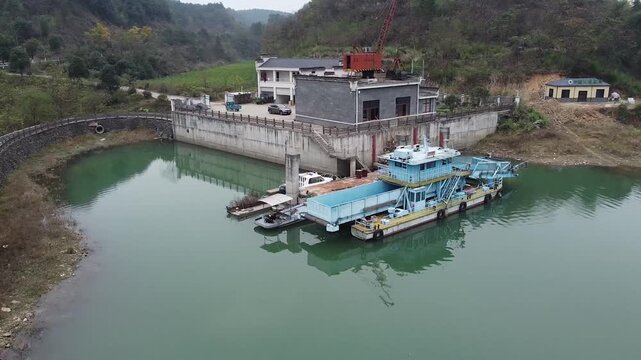 Industrial Dredging Barge Docked at Riverside Facility in Mountain Valley