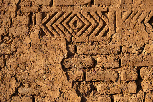 Ancient Moroccan kasbah mud brick wall texture with cracks and earthen patterns close up