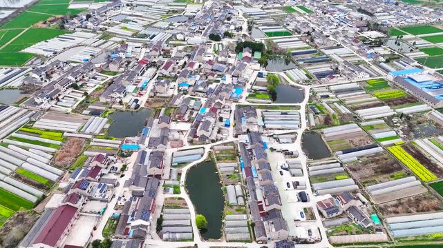 Aerial view of rural village with greenhouses, ponds and farmland