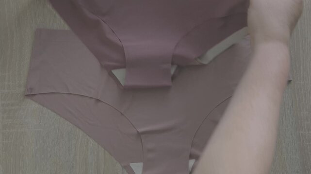 Female hand testing elasticity seamless panties, Woman choosing delicate underwear in shop, Shopping for comfortable lingerie