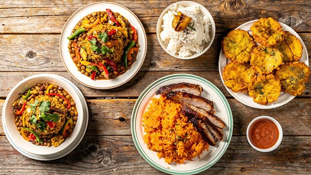A vibrant spread of Dominican food, featuring succulent pork, flavorful rice and beans, crispy tostones, and a hearty lentil stew, is artfully arranged on a rustic wooden table.