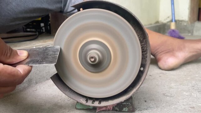 Close-up video of a hand using a grinder to sharpen a knife, showing tool maintenance, metal work, practical repair, and workshop craftsmanship.