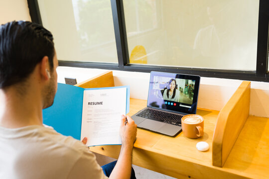 POV of a man having a job interview and discussing resume with recruiter during video call from cafe