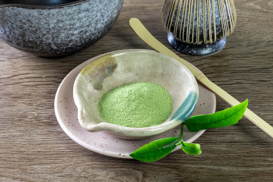 Matcha fine powdered green tea on wooden background.