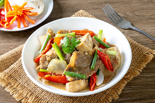 Saut&eacute; the meat in oil in a white plate on a wooden table.