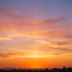 Fototapeta premium A dramatic orange sunset over the city sky with beautiful clouds and warm sunlight during evening dusk