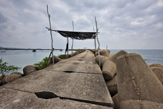 Fishing spot with simple sun shelter on Marang Wave Breaker under dramatic clouds in Terengganu