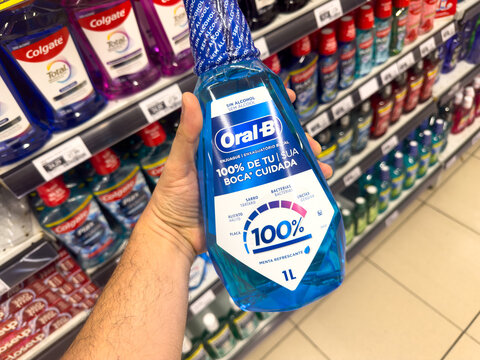 BELO HORIZONTE, MG, BRAZIL, MAY, 15, 2026 A hand holding a bottle of Oral-B mouthwash in a store aisle with various oral care products on shelves