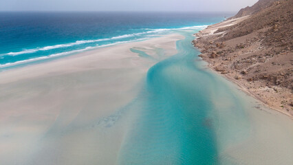 Aerial turquoise lagoon and sandbar along rocky coastline © M