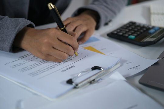 A businesswoman signs a contract. Signing the contract with a pen and her signature on paper, the woman signs several documents to confirm her rights. Financial and business concepts
