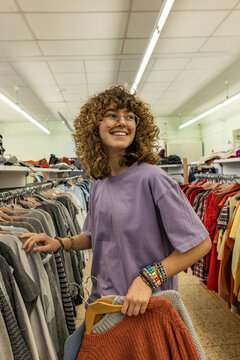 Smiling teenage girl shopping secondhand clothing at a flea market
