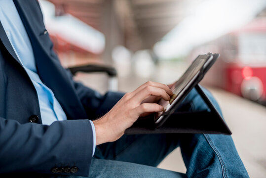 Hand typing on tablet at train station during business trip