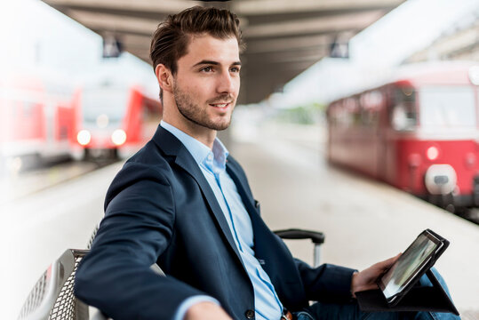 Businessman with tablet waiting at train station