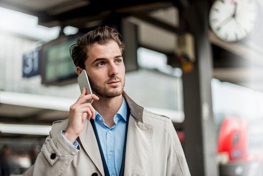 Businessman calling on cell phone at train station