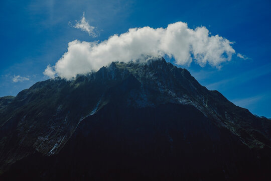 Dramatic mountain peak with a cloud in Milford Sound New Zealand