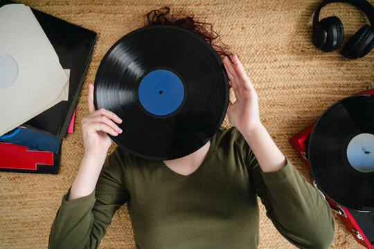 Hiding face behind vinyl record while relaxing on floor
