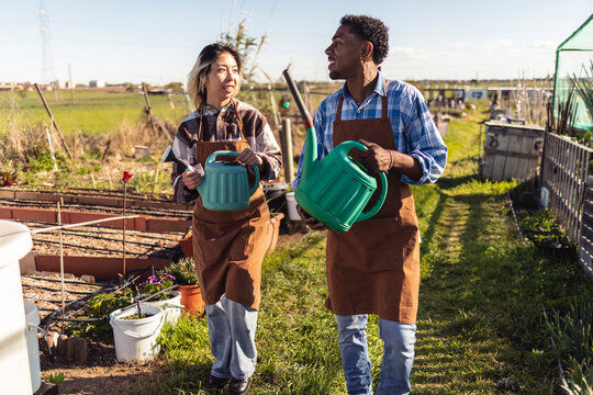Gardeners carrying watering cans walking through organic farm
