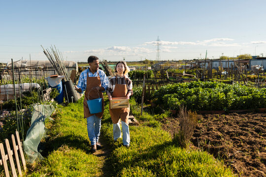 Gardeners walk in a community microfarm with bucket and crate