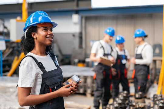 Smiling engineer in hardhat standing in manufacturing factory