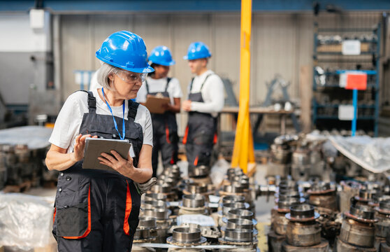 Factory worker inspecting machinery components using a digital tablet