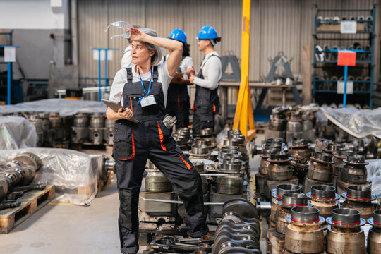 Tired factory worker in coverall resting with digital tablet