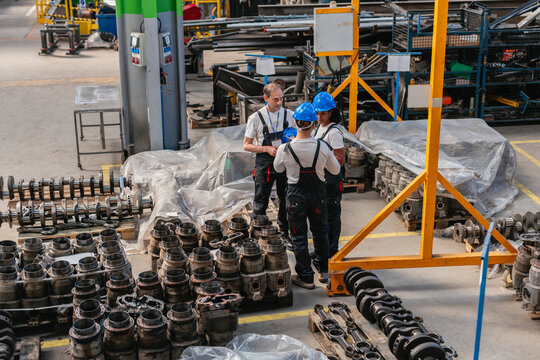 Industrial workers discussing machinery in a manufacturing plant