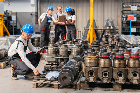Engineers inspecting industrial machinery components indoors